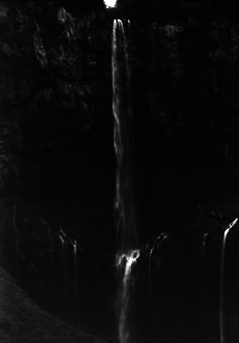 A thin waterfall falling through darkness